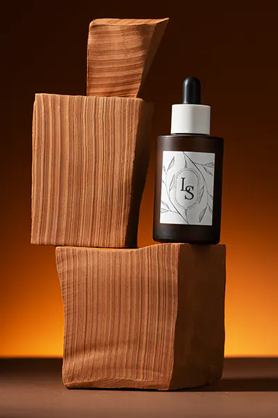 Braunglasflasche mit Pipette inszeniert auf Podesten für professionelle Kosmetik-Produktfotografie.